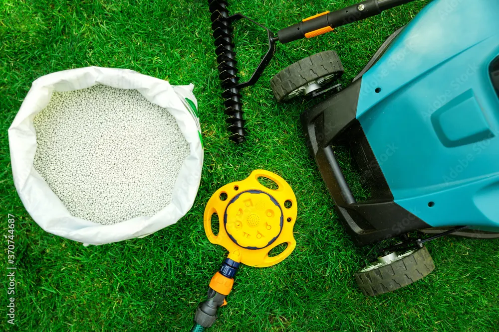 Lawn care tools and equipment laid out on green grass